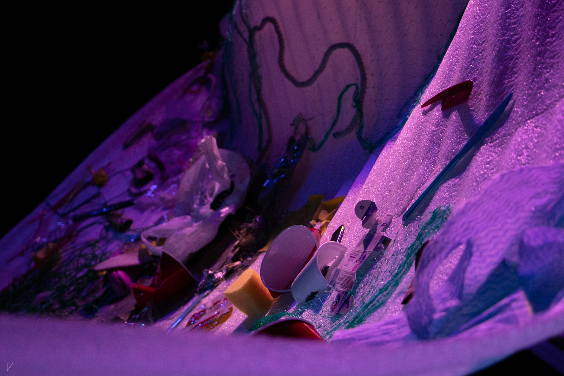 Close up of Drowning Voices set piece, showing details of all the garbage stuck to the sheet, such as plastic cups, fishing net, plastic bags, and more